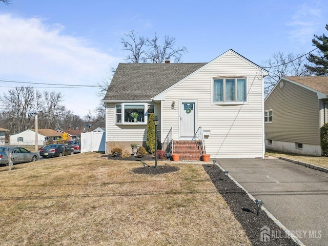 split level home with roof with shingles and a front lawn