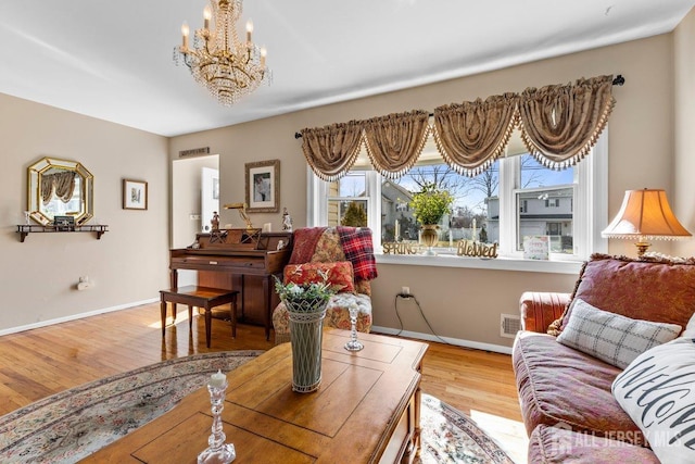 living area with light wood-style floors, a chandelier, visible vents, and baseboards