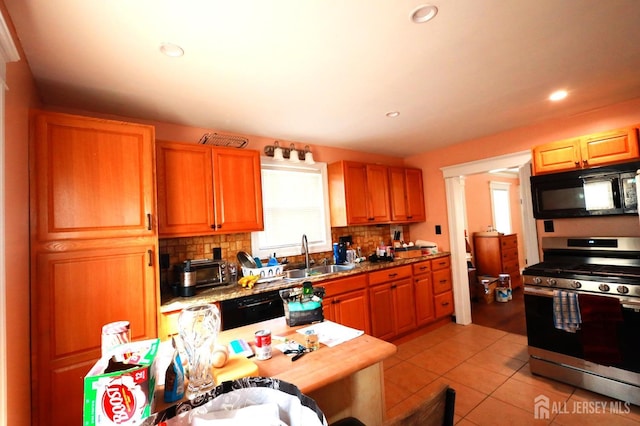 kitchen featuring backsplash, light tile patterned floors, sink, and black appliances