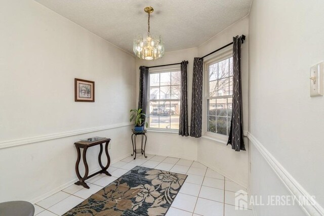 interior space featuring light tile patterned floors, a textured ceiling, and an inviting chandelier