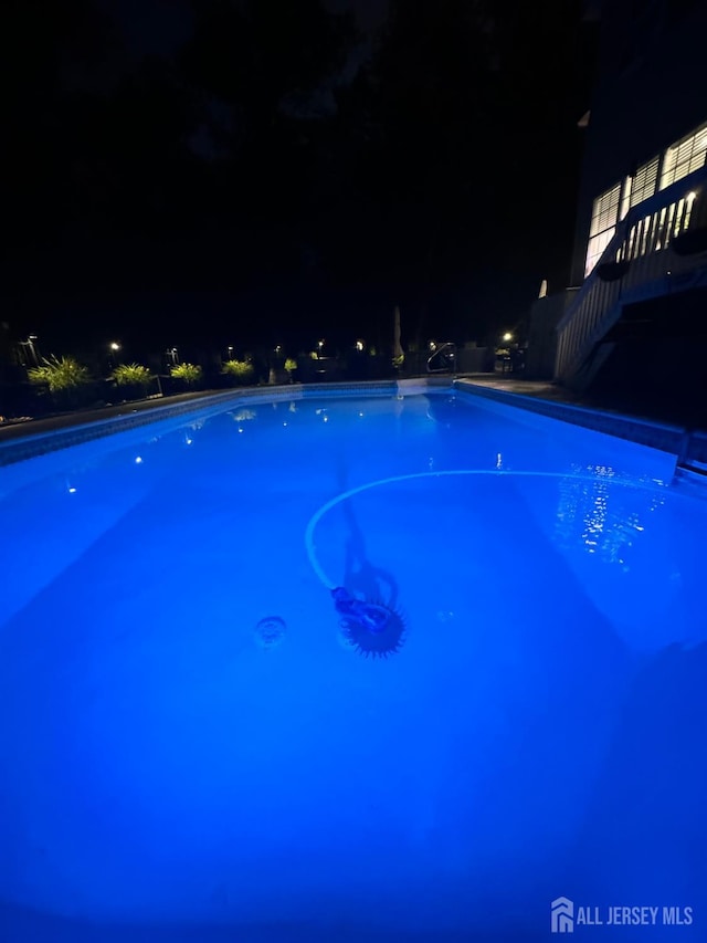 pool at night featuring stairway