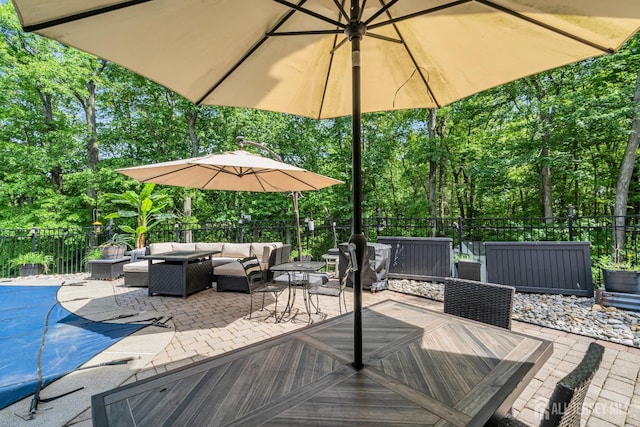 view of patio / terrace with outdoor lounge area, a fenced backyard, outdoor dining area, and view of wooded area