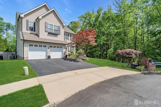 view of front of property featuring a garage, asphalt driveway, central AC, and a front lawn