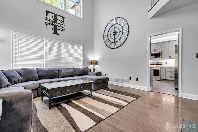 living room with a high ceiling, baseboards, and wood finished floors