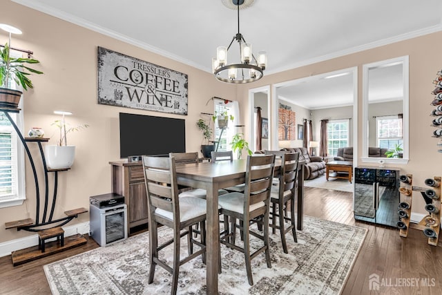 dining area with beverage cooler, ornamental molding, hardwood / wood-style flooring, baseboards, and a chandelier