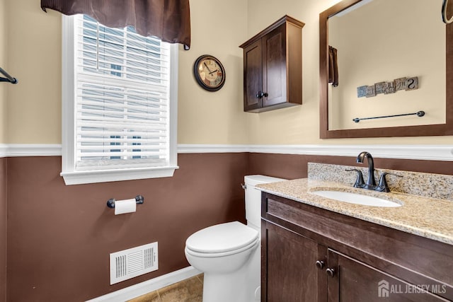 bathroom featuring toilet, healthy amount of natural light, vanity, and baseboards