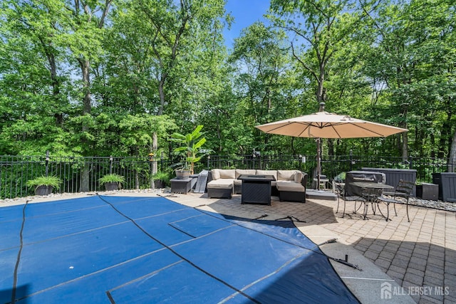 view of patio / terrace with outdoor lounge area, fence, and view of wooded area