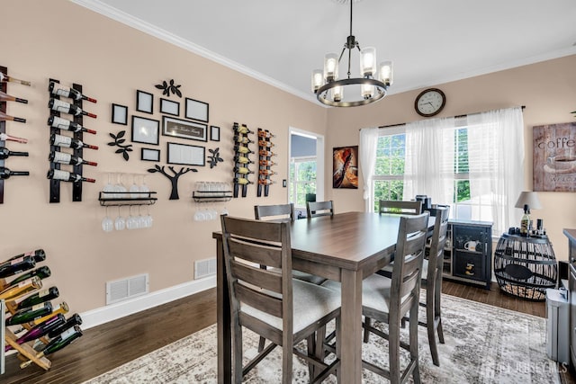 dining area featuring a chandelier, wood finished floors, baseboards, and crown molding