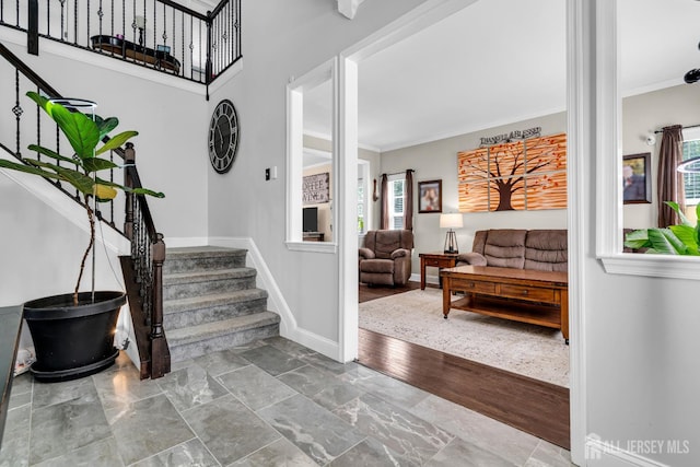 entrance foyer featuring stairs, healthy amount of natural light, crown molding, and baseboards