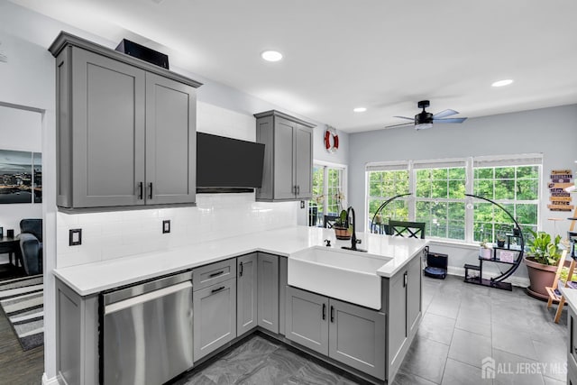 kitchen featuring dishwasher, gray cabinets, a sink, a ceiling fan, and a peninsula