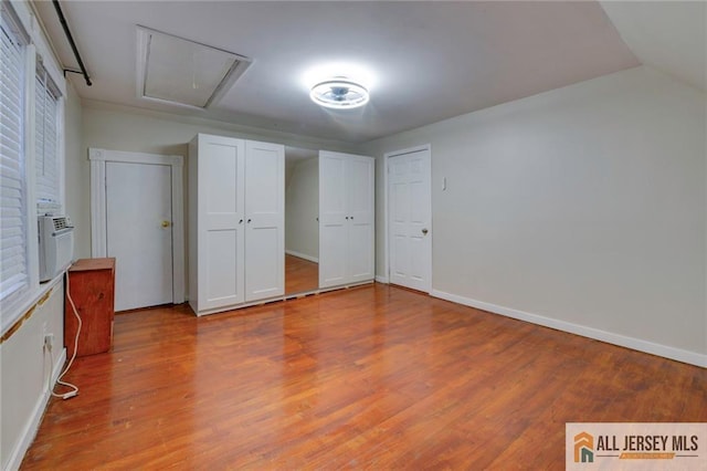 unfurnished bedroom featuring vaulted ceiling, hardwood / wood-style floors, and cooling unit