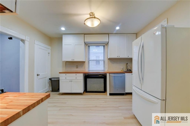 kitchen with butcher block counters, white cabinets, dishwashing machine, white refrigerator, and stainless steel dishwasher