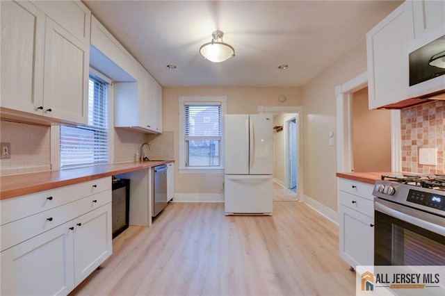 kitchen featuring butcher block countertops, sink, white cabinetry, stainless steel appliances, and light hardwood / wood-style floors