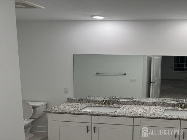 full bathroom with double vanity, toilet, and a sink