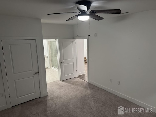 unfurnished bedroom with ensuite bath, a ceiling fan, baseboards, and carpet floors