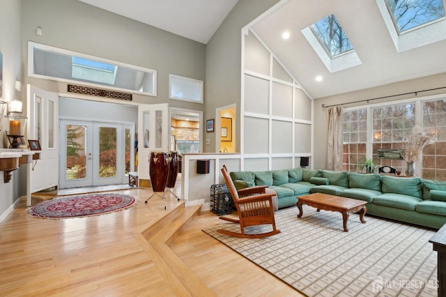 living area featuring a healthy amount of sunlight, high vaulted ceiling, wood finished floors, and french doors