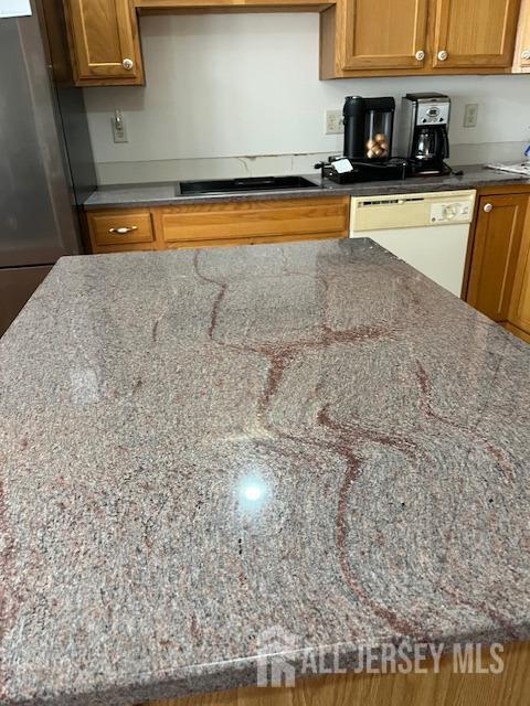 11 Pebble Beach Ct, Monroe, NJ 08831 - kitchen with dark stone counters, white dishwasher, brown cabinetry, and freestanding refrigerator