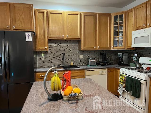 11 Pebble Beach Ct, Monroe, NJ 08831 - kitchen with tasteful backsplash, light stone countertops, a sink, glass insert cabinets, and white appliances