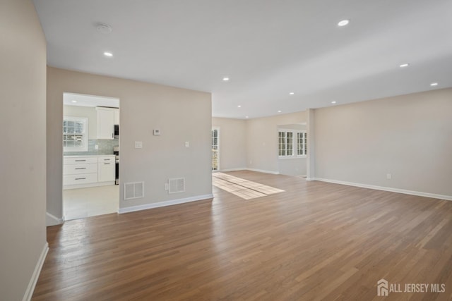 unfurnished living room with light wood-type flooring, visible vents, and recessed lighting