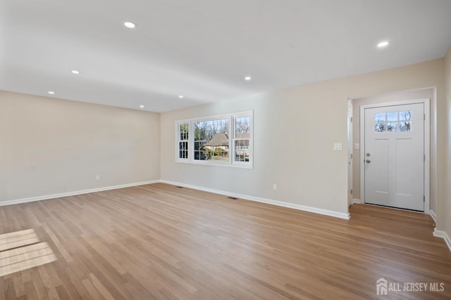 unfurnished living room with recessed lighting, baseboards, and light wood-style floors