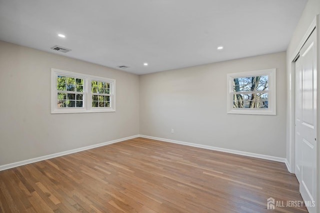 unfurnished room featuring light wood finished floors, visible vents, recessed lighting, and baseboards