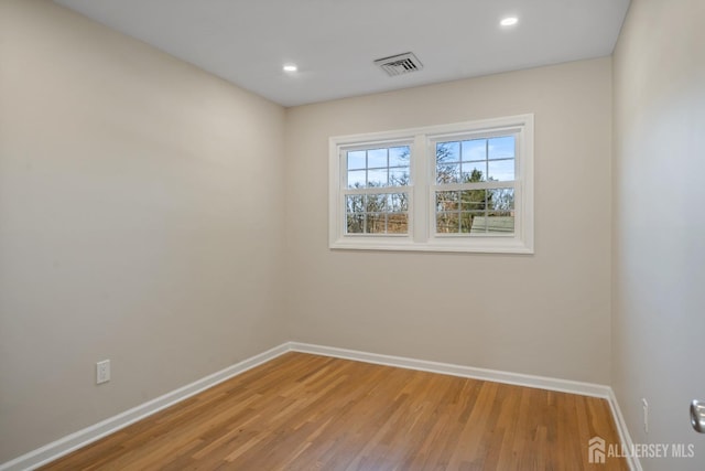 empty room with wood finished floors, recessed lighting, baseboards, and visible vents