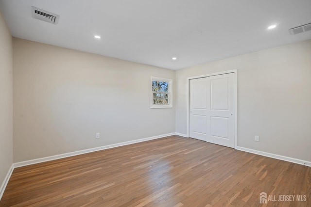 unfurnished bedroom featuring visible vents, baseboards, and wood finished floors