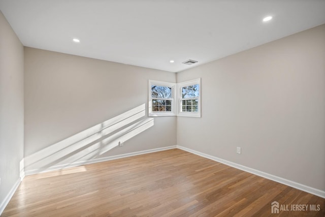 unfurnished room featuring recessed lighting, wood finished floors, visible vents, and baseboards