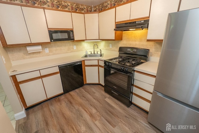 2708 Ridgefield Ct, Helmetta, NJ 08828 - kitchen featuring black appliances, under cabinet range hood, a sink, light wood-style flooring, and light countertops