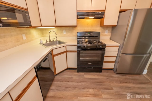 2708 Ridgefield Ct, Helmetta, NJ 08828 - kitchen featuring black appliances, under cabinet range hood, a sink, light countertops, and light wood finished floors