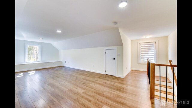 additional living space featuring vaulted ceiling and light hardwood / wood-style flooring