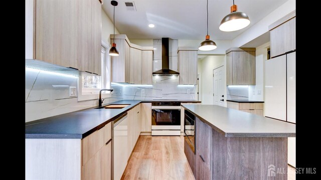 kitchen featuring pendant lighting, light brown cabinets, wall chimney range hood, sink, and white range oven