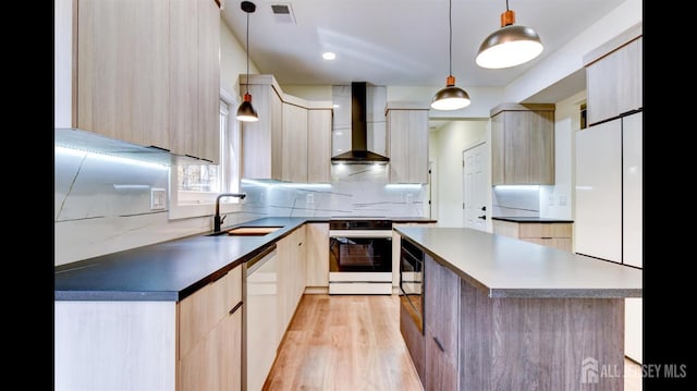 kitchen featuring sink, white appliances, light brown cabinetry, decorative light fixtures, and wall chimney exhaust hood