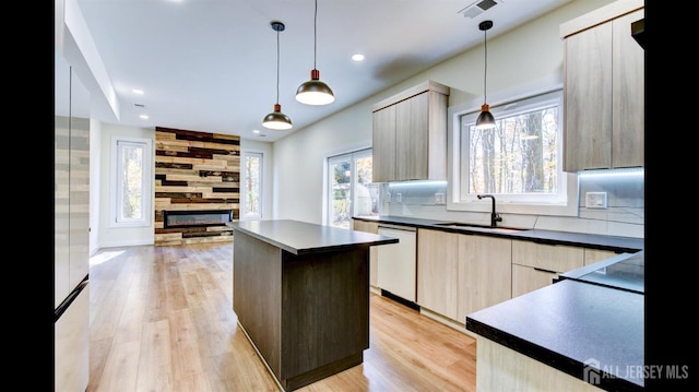 kitchen with a kitchen island, decorative light fixtures, sink, white dishwasher, and light hardwood / wood-style flooring