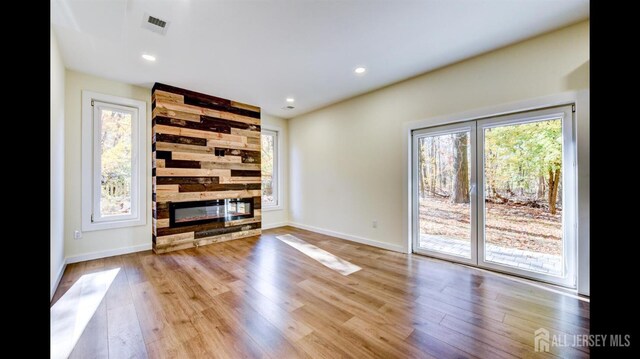 unfurnished living room with a stone fireplace and light hardwood / wood-style floors