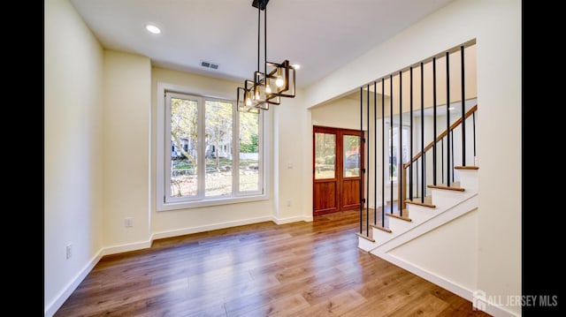 unfurnished dining area with wood-type flooring and a chandelier