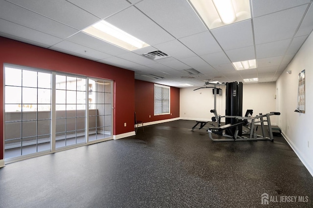 exercise area with visible vents, a paneled ceiling, and baseboards