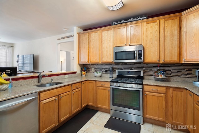 kitchen featuring a sink, light stone counters, stainless steel appliances, light tile patterned flooring, and decorative backsplash