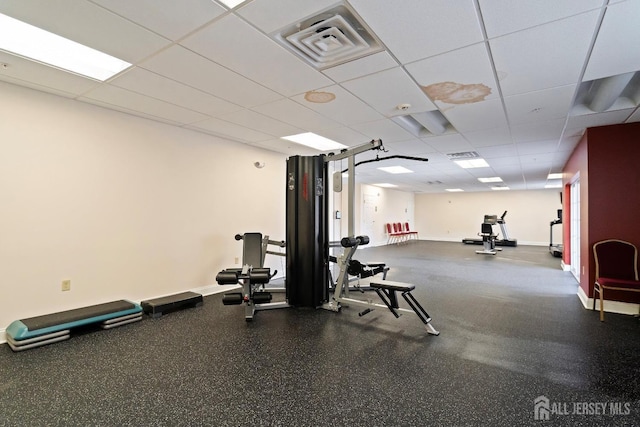 exercise room featuring a paneled ceiling, visible vents, and baseboards