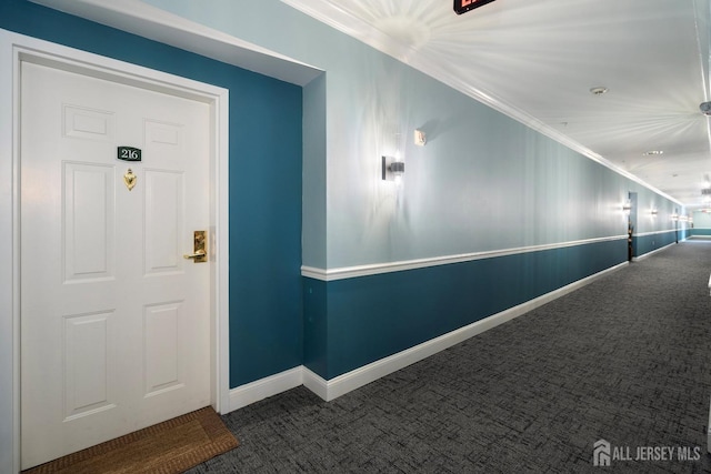 corridor featuring ornamental molding, baseboards, and carpet floors