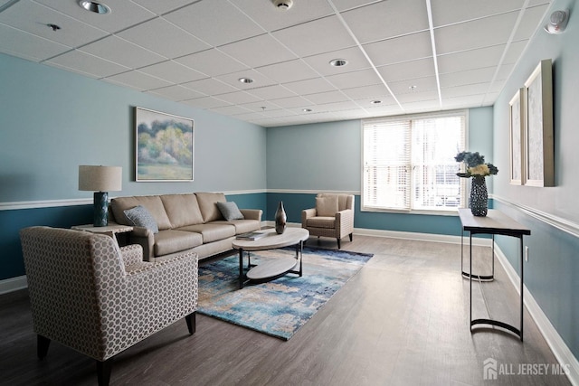 living room with a drop ceiling, baseboards, and wood finished floors