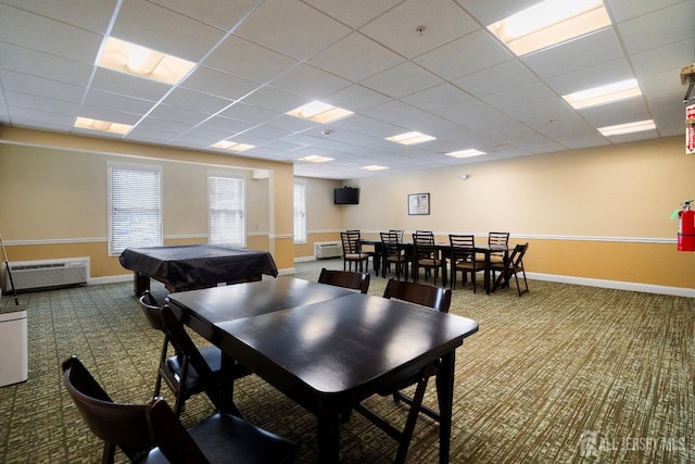 dining area with a drop ceiling, baseboards, carpet, and a wall unit AC