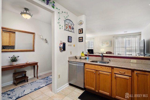 kitchen featuring brown cabinetry, light stone countertops, light tile patterned flooring, a sink, and dishwasher