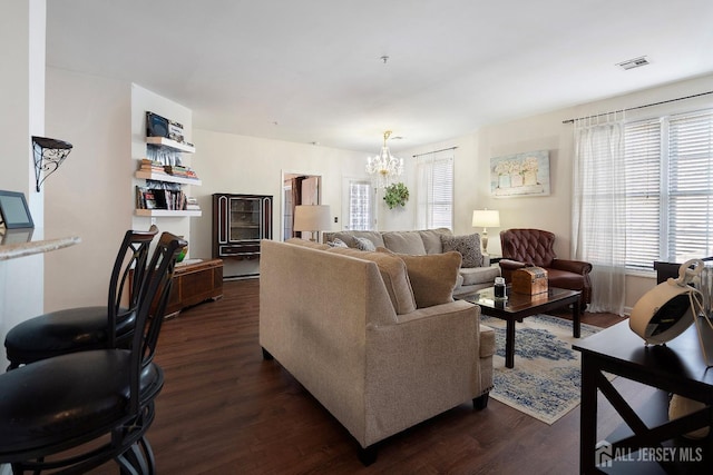 living area with a notable chandelier, visible vents, and dark wood-style flooring