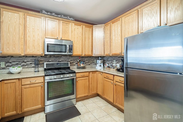 kitchen with light tile patterned floors, appliances with stainless steel finishes, tasteful backsplash, and light stone counters