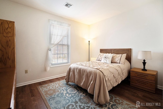 bedroom with wood finished floors, visible vents, and baseboards