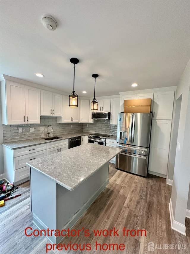 kitchen with pendant lighting, a center island, sink, appliances with stainless steel finishes, and white cabinetry