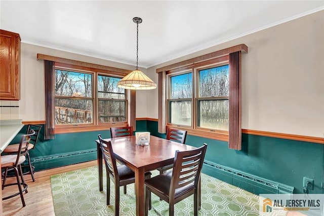 dining area with ornamental molding and light wood-style floors