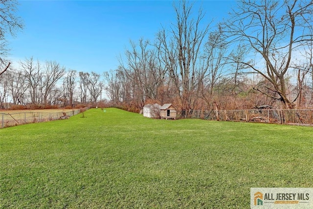 view of yard featuring fence, an outdoor structure, and a shed