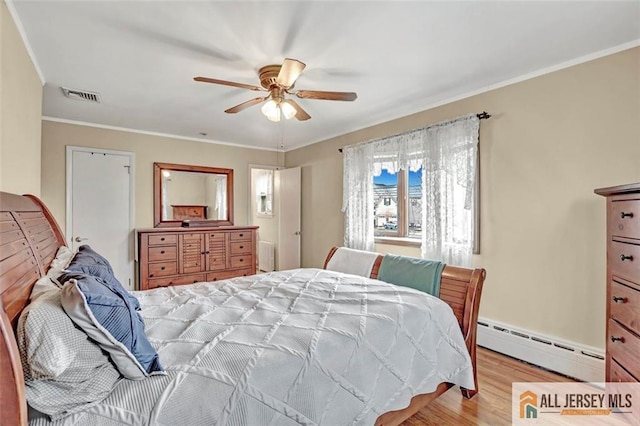 bedroom featuring light wood-type flooring, visible vents, a baseboard heating unit, and crown molding